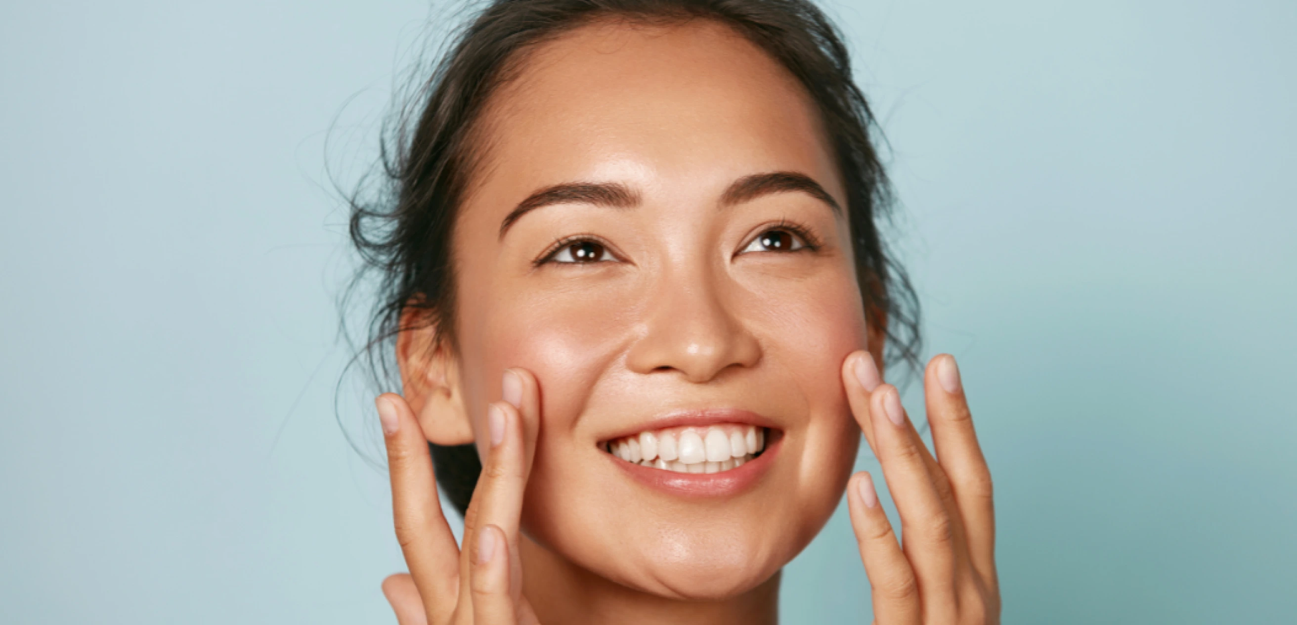 A woman resting her fingertips against her cheeks.